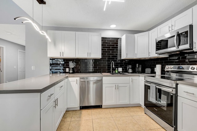 5682 25th Street Cir E, Bradenton, FL 34203 - kitchen with appliances with stainless steel finishes, a peninsula, decorative backsplash, white cabinetry, and light tile patterned floors
