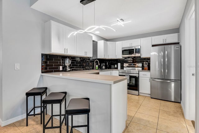 5682 25th Street Cir E, Bradenton, FL 34203 - kitchen featuring stainless steel appliances, a peninsula, backsplash, a kitchen bar, and white cabinets