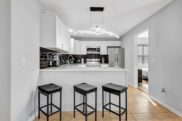 5682 25th Street Cir E, Bradenton, FL 34203 - kitchen with stainless steel appliances, backsplash, a peninsula, light countertops, and light tile patterned floors