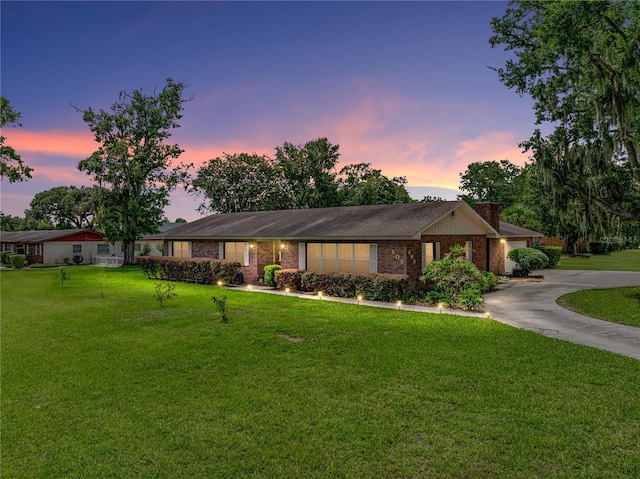 609 W Pipkin Rd, Lakeland, FL 33813 - ranch-style house with curved driveway, a lawn, and brick siding