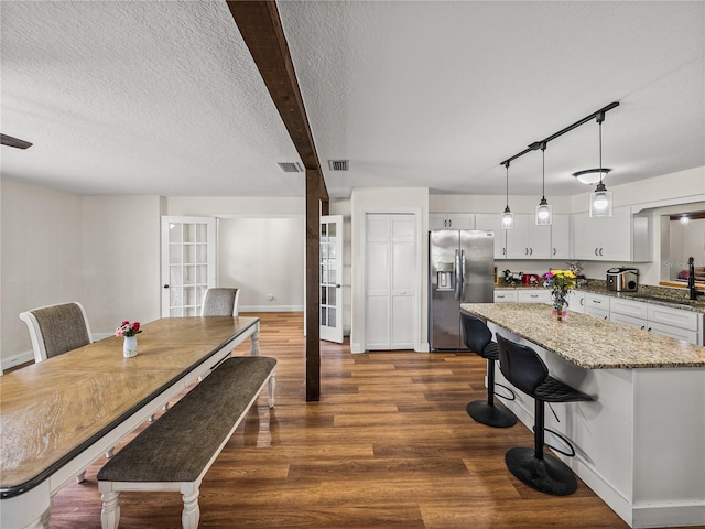 609 W Pipkin Rd, Lakeland, FL 33813 - kitchen with stainless steel fridge, dark wood-type flooring, a kitchen island, light stone counters, and white cabinets