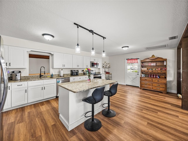 609 W Pipkin Rd, Lakeland, FL 33813 - kitchen with appliances with stainless steel finishes, white cabinets, a kitchen bar, and wood finished floors