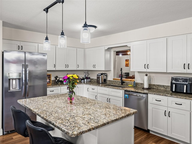 609 W Pipkin Rd, Lakeland, FL 33813 - kitchen featuring stainless steel appliances, dark wood-style floors, a breakfast bar area, white cabinets, and a textured ceiling