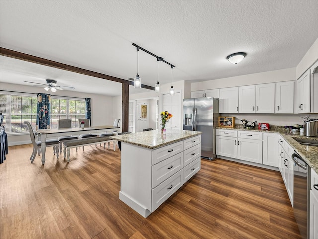 609 W Pipkin Rd, Lakeland, FL 33813 - kitchen with appliances with stainless steel finishes, a kitchen island, dark wood-type flooring, light stone counters, and a textured ceiling