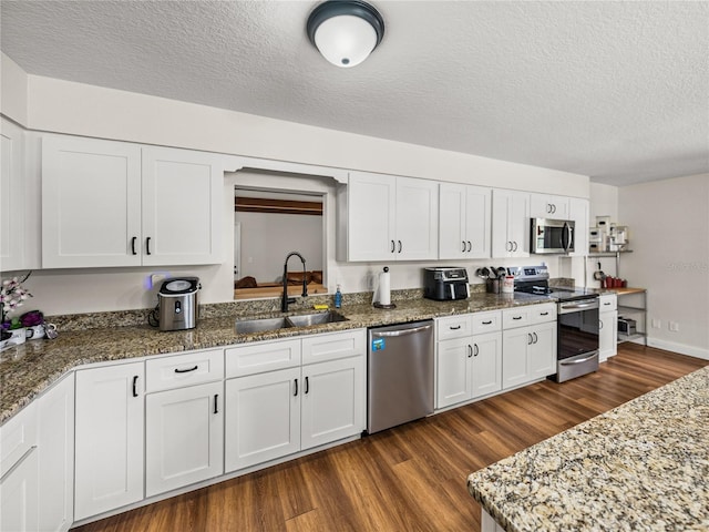609 W Pipkin Rd, Lakeland, FL 33813 - kitchen with stainless steel appliances, dark wood-type flooring, a textured ceiling, and white cabinetry