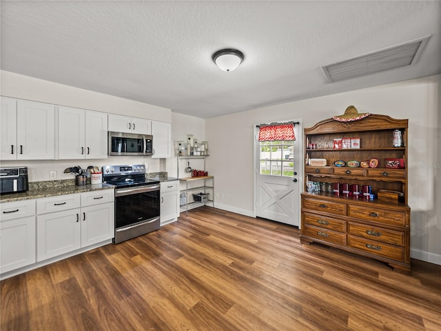609 W Pipkin Rd, Lakeland, FL 33813 - kitchen with stainless steel appliances, dark wood finished floors, white cabinetry, dark stone counters, and a textured ceiling