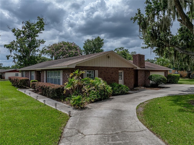 609 W Pipkin Rd, Lakeland, FL 33813 - view of front facade with concrete driveway, brick siding, a front yard, and a chimney