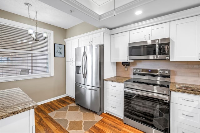 6399 Shoreline Dr Unit 4201, Saint Petersburg, FL 33708 - kitchen featuring appliances with stainless steel finishes, tasteful backsplash, wood finished floors, and white cabinets