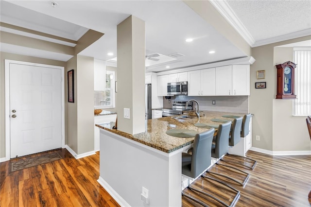 6399 Shoreline Dr Unit 4201, Saint Petersburg, FL 33708 - kitchen with appliances with stainless steel finishes, ornamental molding, light stone countertops, white cabinets, and dark wood finished floors
