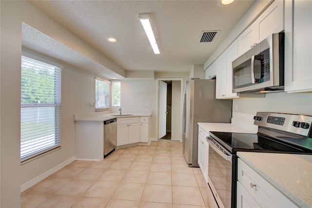 2442 Dando St, Port Charlotte, FL 33948 - kitchen featuring stainless steel appliances, white cabinets, light tile patterned floors, a textured ceiling, and recessed lighting