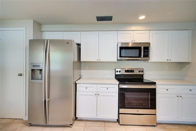 2442 Dando St, Port Charlotte, FL 33948 - kitchen with stainless steel appliances, light countertops, white cabinets, light tile patterned floors, and recessed lighting