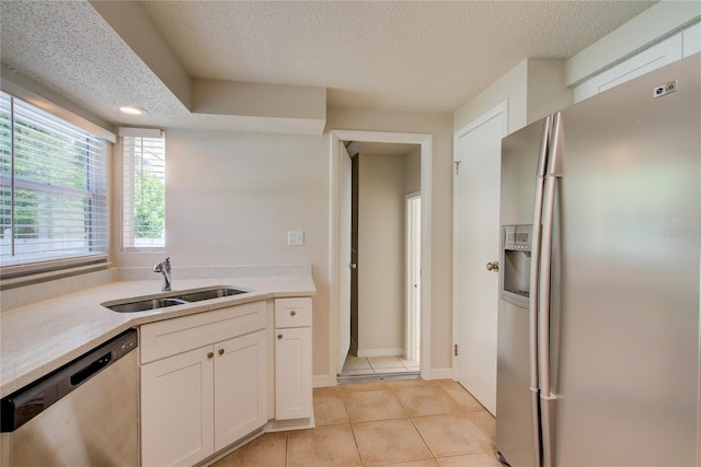 2442 Dando St, Port Charlotte, FL 33948 - kitchen with stainless steel appliances, a textured ceiling, light tile patterned floors, white cabinets, and light countertops