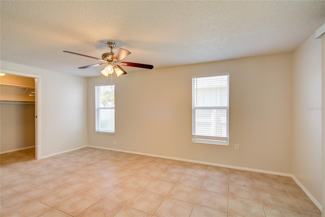 2442 Dando St, Port Charlotte, FL 33948 - unfurnished bedroom with a spacious closet, a textured ceiling, a ceiling fan, and light tile patterned floors