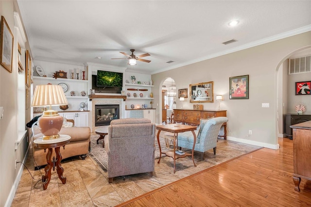 828 E Savoy St, Lecanto, FL 34461 - living area featuring arched walkways, ceiling fan, crown molding, a fireplace, and light wood-style floors
