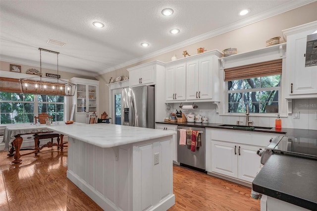 828 E Savoy St, Lecanto, FL 34461 - kitchen featuring stainless steel appliances, white cabinetry, ornamental molding, a kitchen island, and light wood finished floors