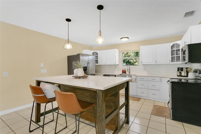 4233 Oak Ln, Saint Augustine, FL 32086 - kitchen with stainless steel appliances, glass insert cabinets, white cabinetry, light countertops, and pendant lighting