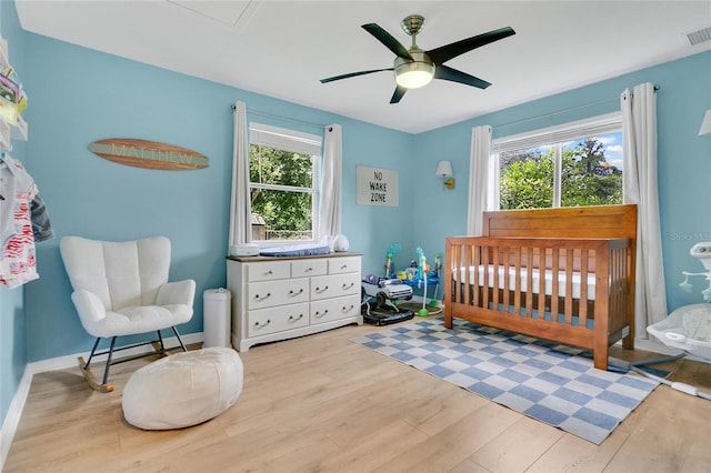 4233 Oak Ln, Saint Augustine, FL 32086 - bedroom featuring wood finished floors, multiple windows, a nursery area, and ceiling fan