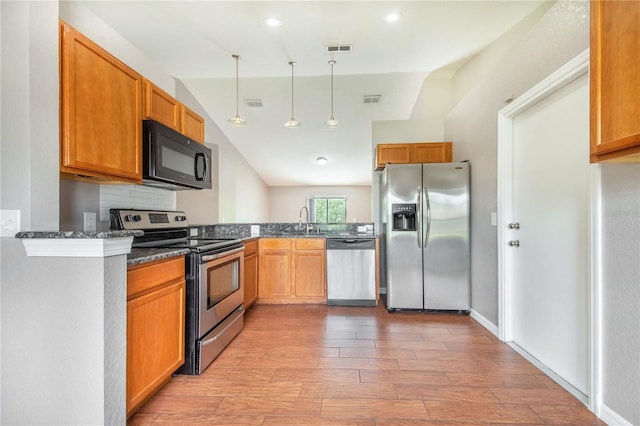 161 Oak Crossing Blvd, Auburndale, FL 33823 - kitchen featuring appliances with stainless steel finishes, light wood-style floors, dark stone counters, pendant lighting, and lofted ceiling