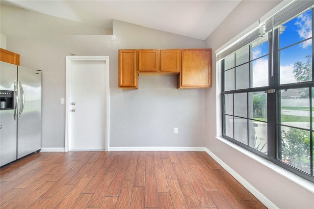 161 Oak Crossing Blvd, Auburndale, FL 33823 - kitchen featuring stainless steel fridge, wood finished floors, vaulted ceiling, and brown cabinets