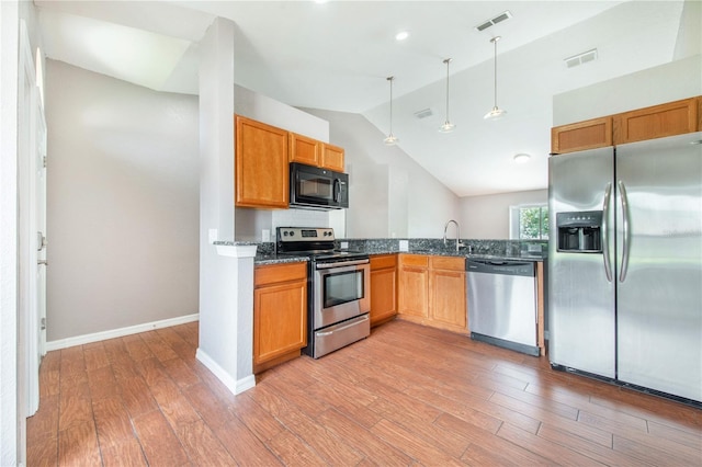 161 Oak Crossing Blvd, Auburndale, FL 33823 - kitchen featuring appliances with stainless steel finishes, light wood-style flooring, vaulted ceiling, hanging light fixtures, and dark stone counters