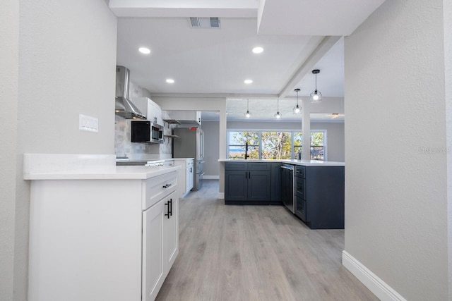 809 59th Ave, Saint Petersburg, FL 33706 - kitchen with wall chimney exhaust hood, appliances with stainless steel finishes, light countertops, light wood-style flooring, and recessed lighting