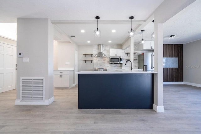 809 59th Ave, Saint Petersburg, FL 33706 - kitchen featuring appliances with stainless steel finishes, wall chimney exhaust hood, tasteful backsplash, white cabinetry, and recessed lighting