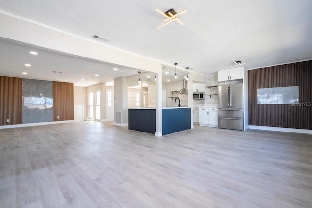 809 59th Ave, Saint Petersburg, FL 33706 - unfurnished living room featuring light wood-style flooring, recessed lighting, a textured ceiling, and wood walls