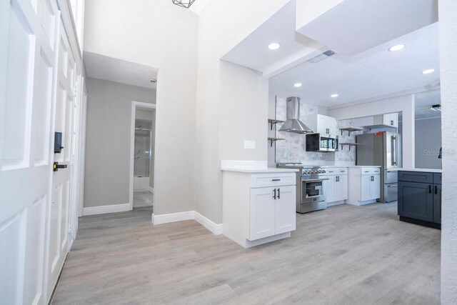 809 59th Ave, Saint Petersburg, FL 33706 - kitchen with appliances with stainless steel finishes, wall chimney range hood, tasteful backsplash, light wood finished floors, and light countertops