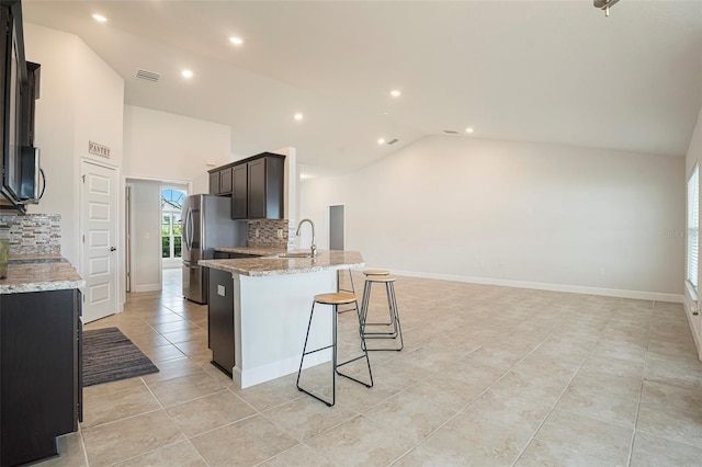 11539 Sunder Berry St, Hudson, FL 34667 - kitchen featuring vaulted ceiling, tasteful backsplash, a kitchen bar, light tile patterned floors, and light stone counters