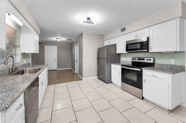 607 Spring Blossom Ct, Brandon, FL 33511 - kitchen with stainless steel appliances, white cabinetry, a textured ceiling, light stone counters, and light tile patterned floors