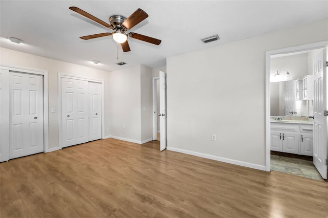 607 Spring Blossom Ct, Brandon, FL 33511 - unfurnished bedroom featuring two closets, wood finished floors, and ensuite bath