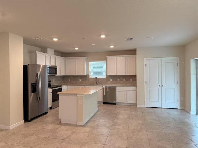 905 Rivers Crossing St, Clermont, FL 34714 - kitchen with appliances with stainless steel finishes, light countertops, tasteful backsplash, white cabinetry, and a kitchen island
