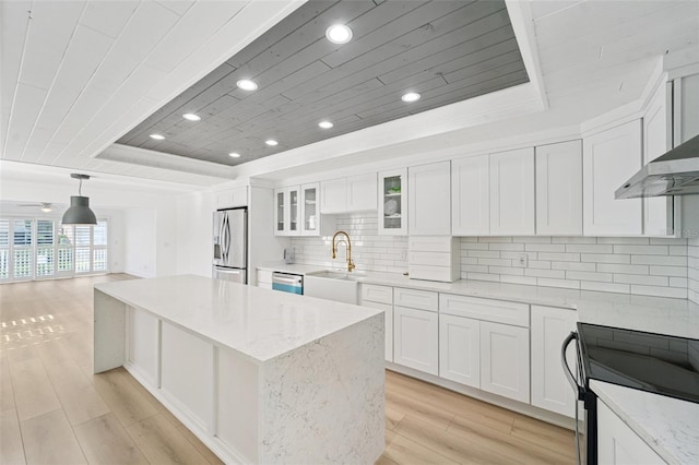 9410 Tara Cay Ct Unit 15, Seminole, FL 33776 - kitchen featuring a raised ceiling, stainless steel appliances, wood ceiling, a kitchen island, and light wood-style flooring