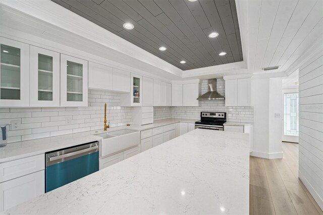 9410 Tara Cay Ct Unit 15, Seminole, FL 33776 - kitchen with stainless steel range with electric cooktop, dishwasher, wall chimney exhaust hood, a tray ceiling, and light wood-style floors