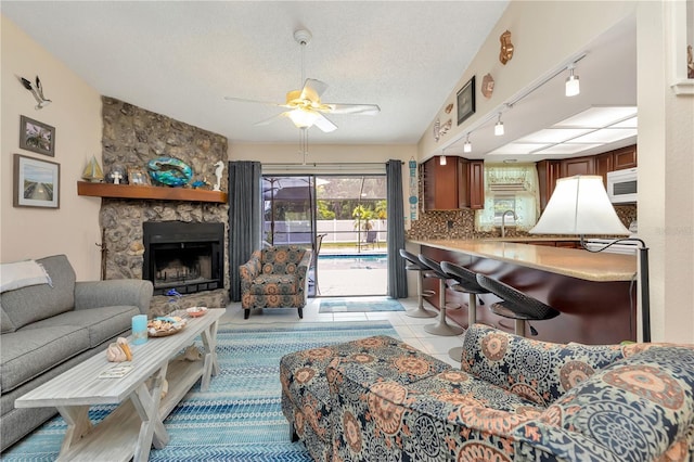 5319 Cordova Way S, Saint Petersburg, FL 33712 - living room featuring rail lighting, a ceiling fan, a stone fireplace, a textured ceiling, and light tile patterned floors