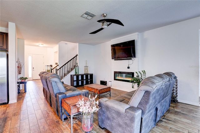 10146 Tuscan Sun Ave, Riverview, FL 33578 - living room featuring light wood-type flooring, a ceiling fan, a fireplace, and stairway