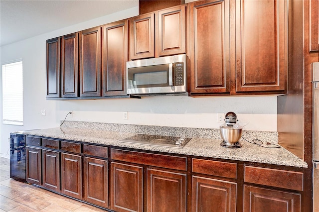 10146 Tuscan Sun Ave, Riverview, FL 33578 - kitchen with stainless steel microwave, black electric stovetop, and light stone counters