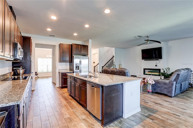 10146 Tuscan Sun Ave, Riverview, FL 33578 - kitchen featuring appliances with stainless steel finishes, light wood finished floors, a glass covered fireplace, open floor plan, and recessed lighting