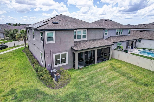 10146 Tuscan Sun Ave, Riverview, FL 33578 - rear view of house with stucco siding, a sunroom, a shingled roof, and roof mounted solar panels