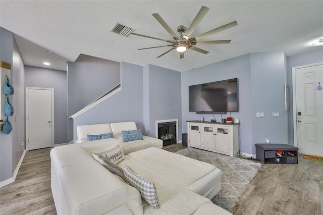 6314 Magnolia Trails Ln, Gibsonton, FL 33534 - living room featuring ceiling fan, wood finished floors, a glass covered fireplace, and a textured ceiling