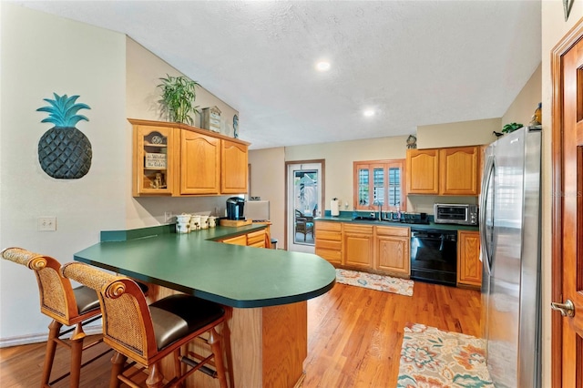 1008 Mallow Way, Brandon, FL 33510 - kitchen featuring black dishwasher, freestanding refrigerator, a peninsula, a breakfast bar area, and light wood finished floors