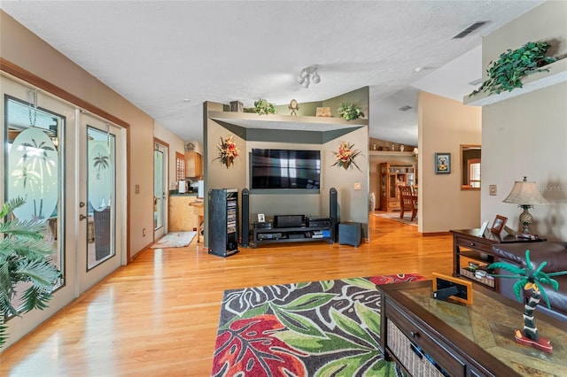 1008 Mallow Way, Brandon, FL 33510 - living room with light wood-type flooring, vaulted ceiling, a textured ceiling, and french doors