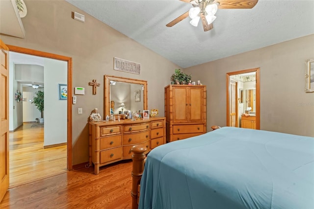1008 Mallow Way, Brandon, FL 33510 - bedroom featuring light wood-style floors, vaulted ceiling, a textured ceiling, a ceiling fan, and ensuite bath