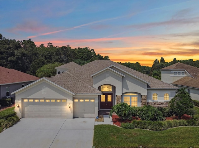 5321 Silver Charm Ter, Wesley Chapel, FL 33544 - view of front of house featuring stucco siding, an attached garage, driveway, stone siding, and a shingled roof