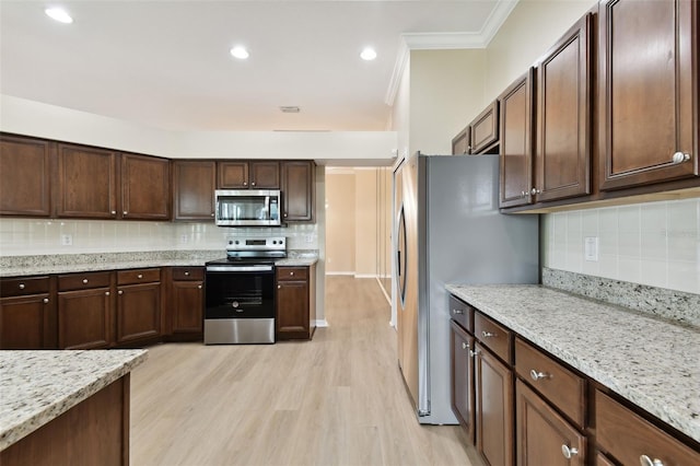 5321 Silver Charm Ter, Wesley Chapel, FL 33544 - kitchen with stainless steel appliances, backsplash, light wood finished floors, dark brown cabinets, and ornamental molding