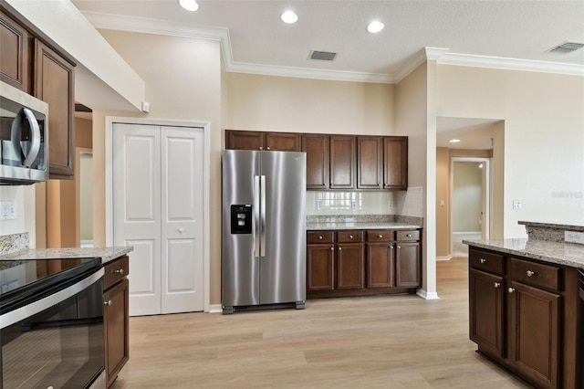 5321 Silver Charm Ter, Wesley Chapel, FL 33544 - kitchen featuring appliances with stainless steel finishes, crown molding, light wood finished floors, dark brown cabinets, and tasteful backsplash