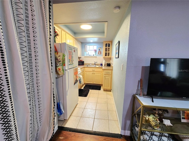 1205 Omaha Cir, Palm Harbor, FL 34683 - kitchen with freestanding refrigerator, a tray ceiling, a textured wall, black microwave, and light brown cabinets