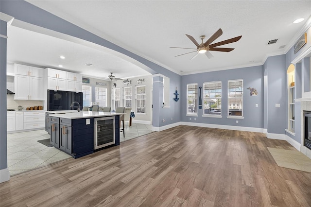 5720 Tortoise Pl, Apollo Beach, FL 33572 - kitchen with ceiling fan, wine cooler, open floor plan, white cabinetry, and light countertops