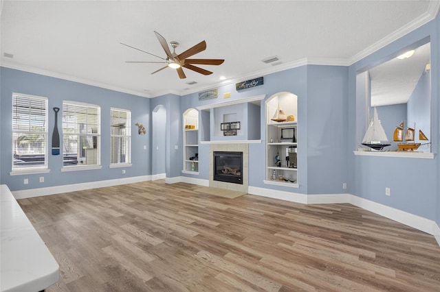 5720 Tortoise Pl, Apollo Beach, FL 33572 - unfurnished living room with ceiling fan, wood finished floors, ornamental molding, built in features, and a tile fireplace