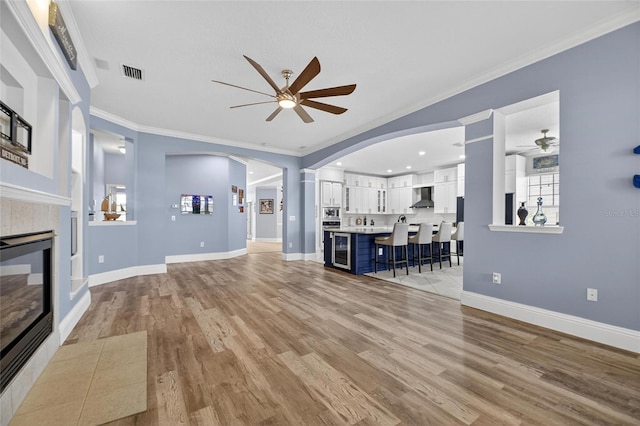 5720 Tortoise Pl, Apollo Beach, FL 33572 - unfurnished living room with ceiling fan, a fireplace, ornamental molding, light wood-type flooring, and beverage cooler
